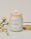 Candle in a jar labeled 'Ivy & Willow Botanicals' with flowers on a light background