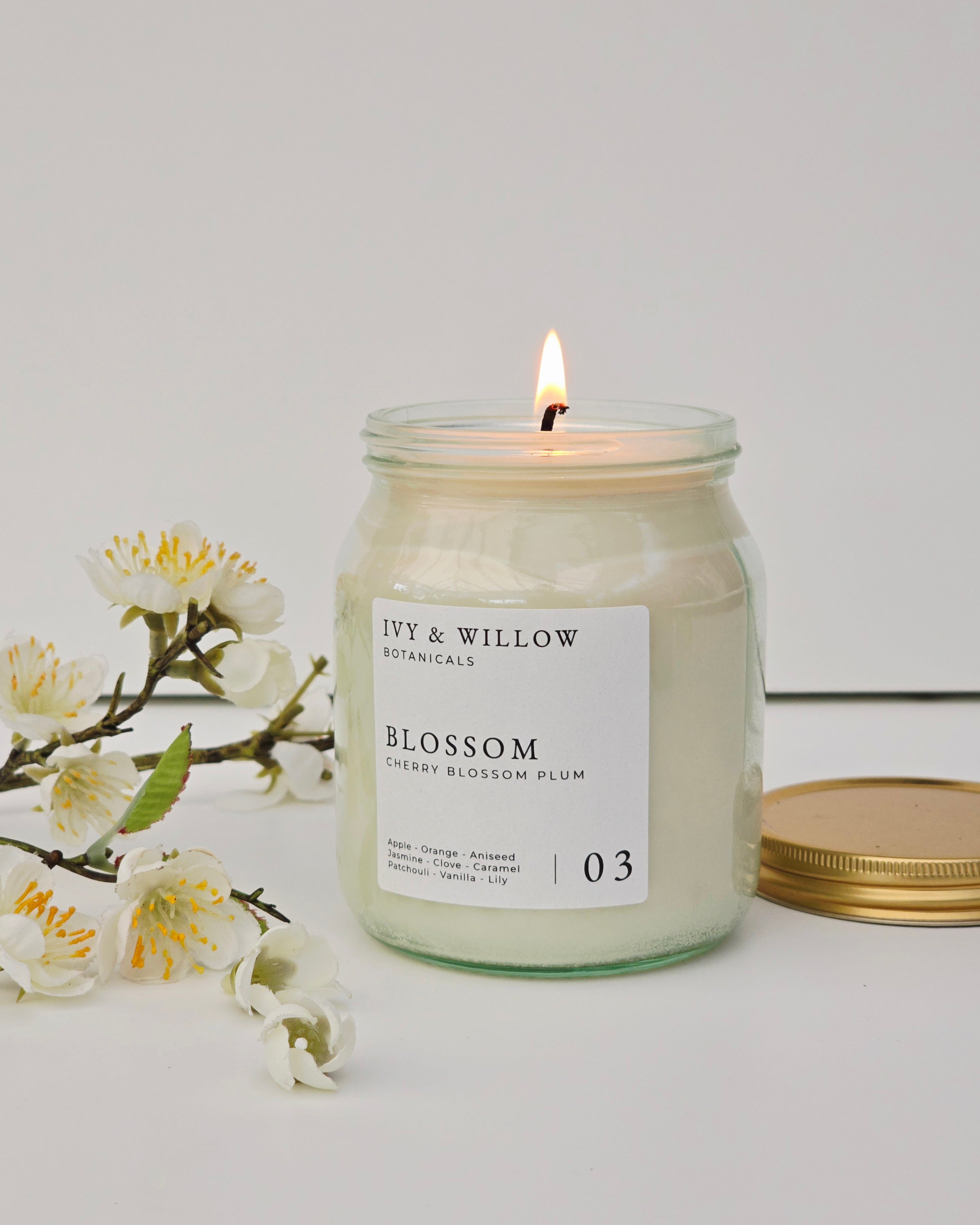 Ivy & Willow Botanicals candle with a floral branch on a white background