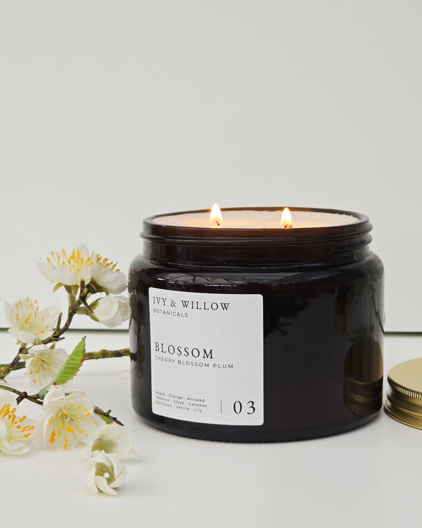 Black candle jar with 'Lily & Willow' label and white flowers on a light gray background