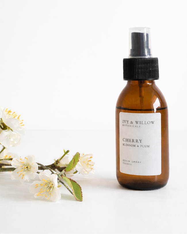 Brown spray bottle with a label on a white background with white flowers.