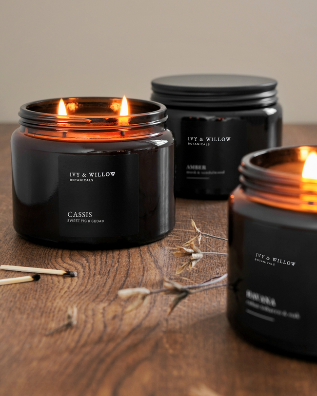 Black candles with 'Ivy & Willow' branding on a wooden surface.