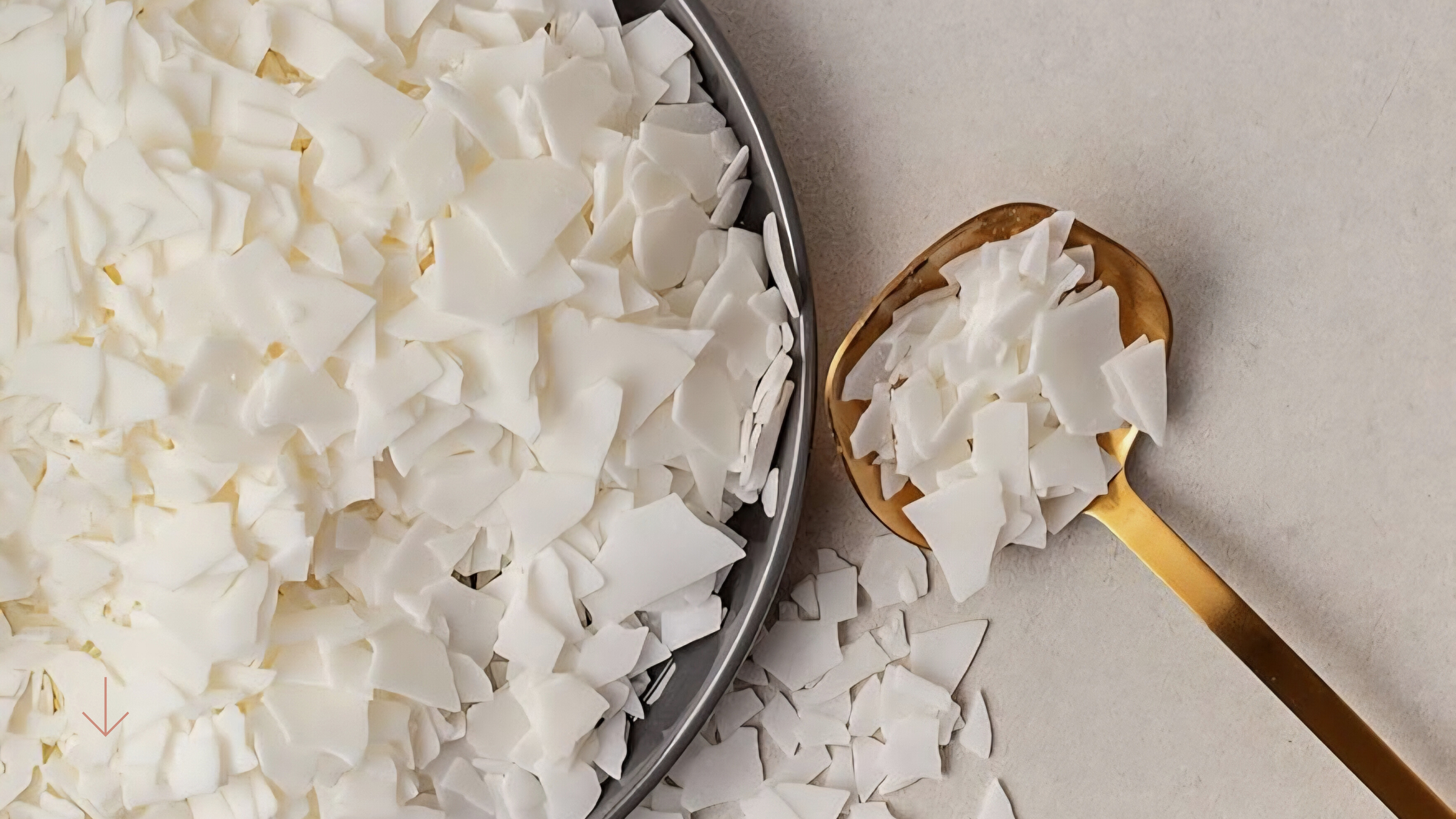 Coconut flakes in a bowl and on a spoon against a neutral background