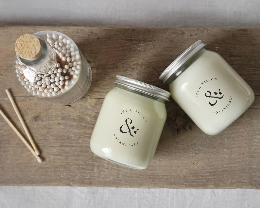 Two jars with silver lids on a wooden surface, accompanied by a bottle of matches and wooden sticks.