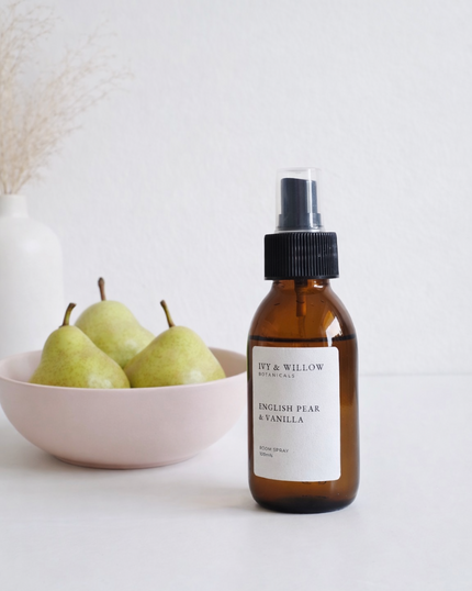 Brown bottle with a label next to a bowl of pears on a light background