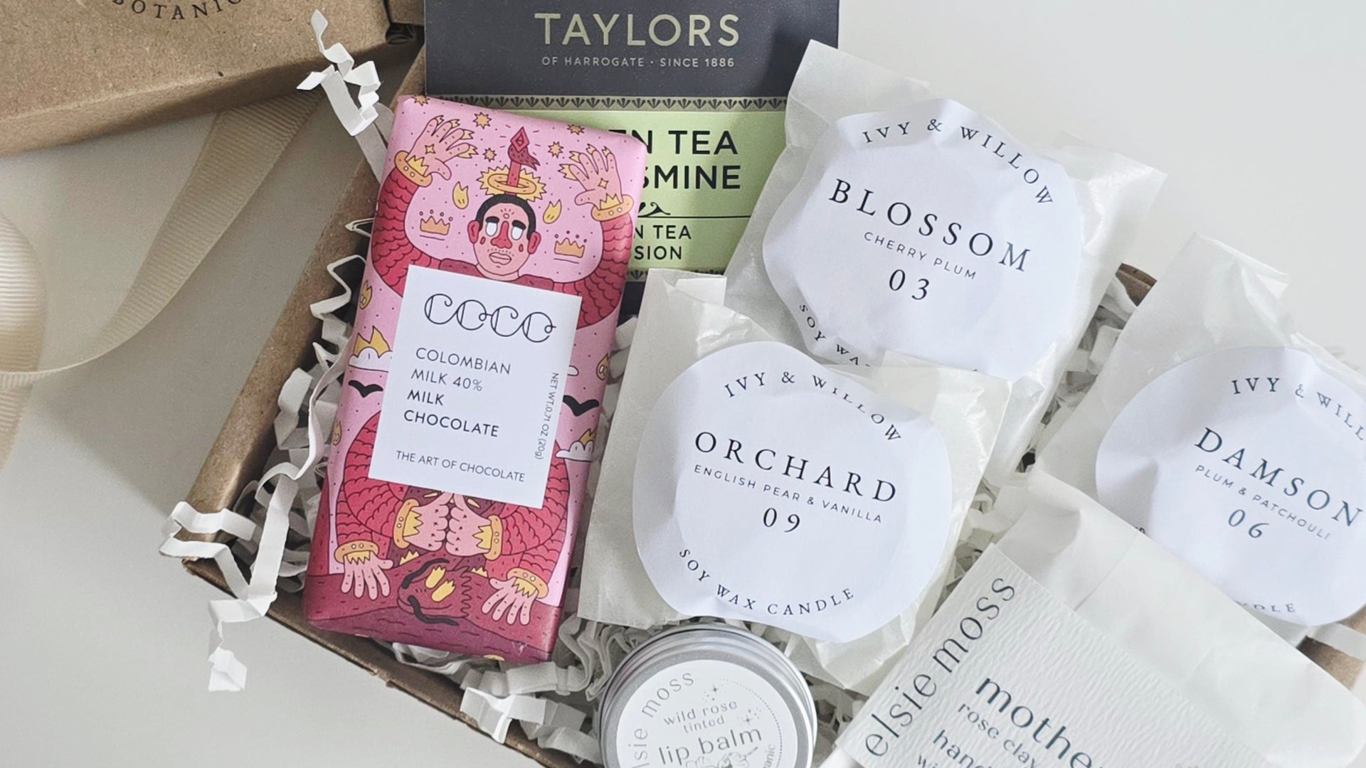 Gift box with chocolate bar, tea bags, and candles on a white background