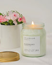 Candle in a jar labeled 'Ivy & Willow Botanicals' with a potted plant in the background