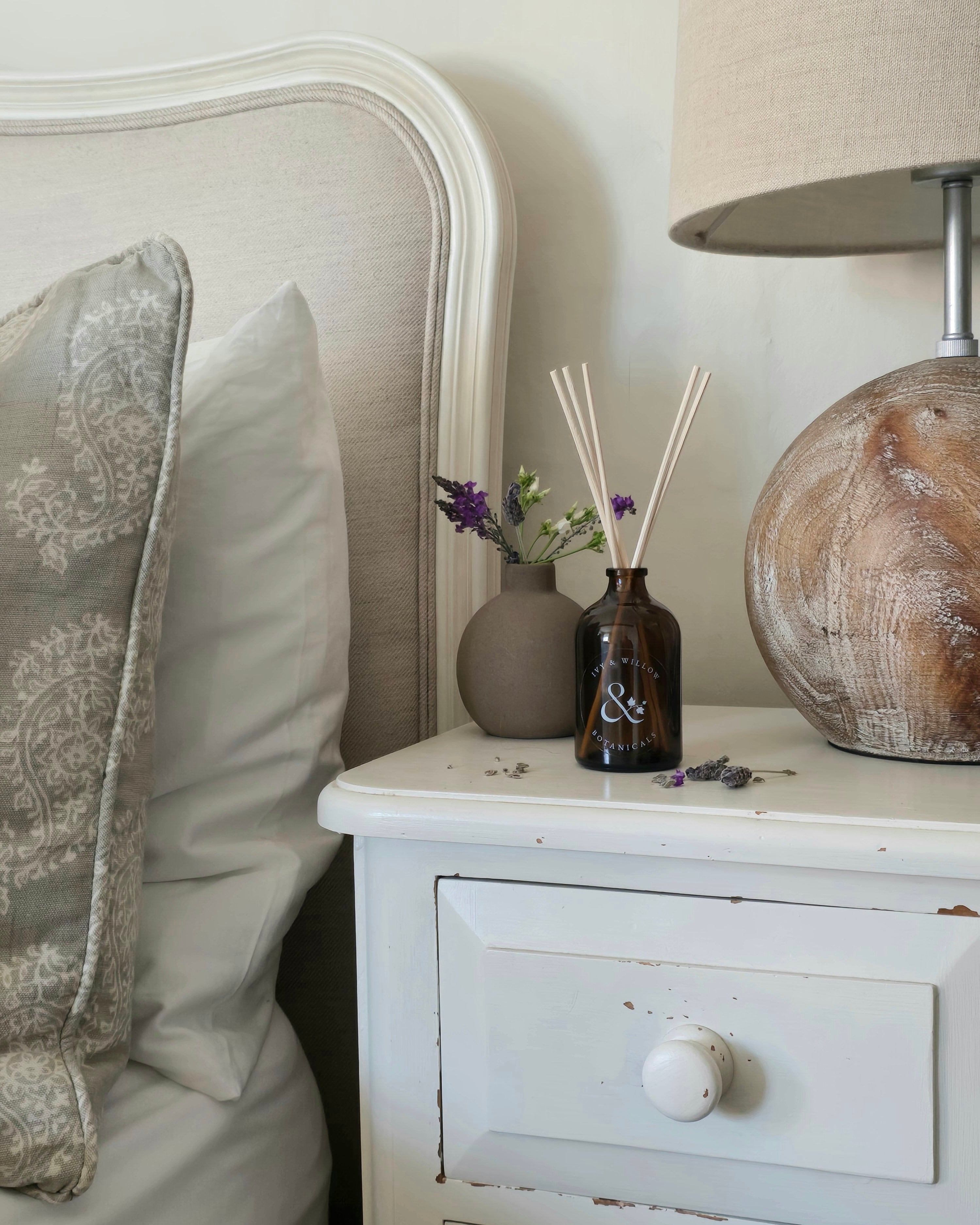 Napkin holder with decorative items on a nightstand next to a bed