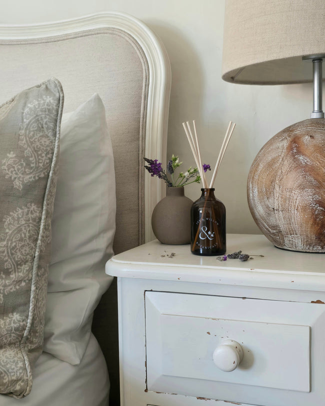 Napkin holder with decorative items on a nightstand next to a bed
