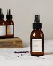 Brown pillow mist spray bottle with a label on a white surface, with additional bottles in the background.
