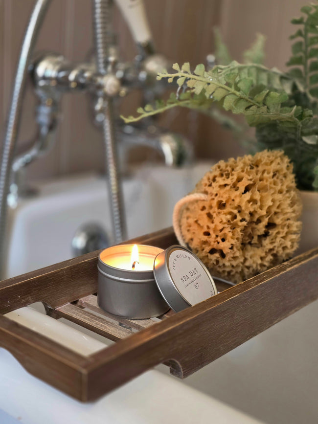 Candle in a tin with a wooden tray in a bathroom setting