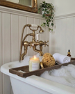 Bathroom setup with a bathtub, candles, and towels on a wooden tray.