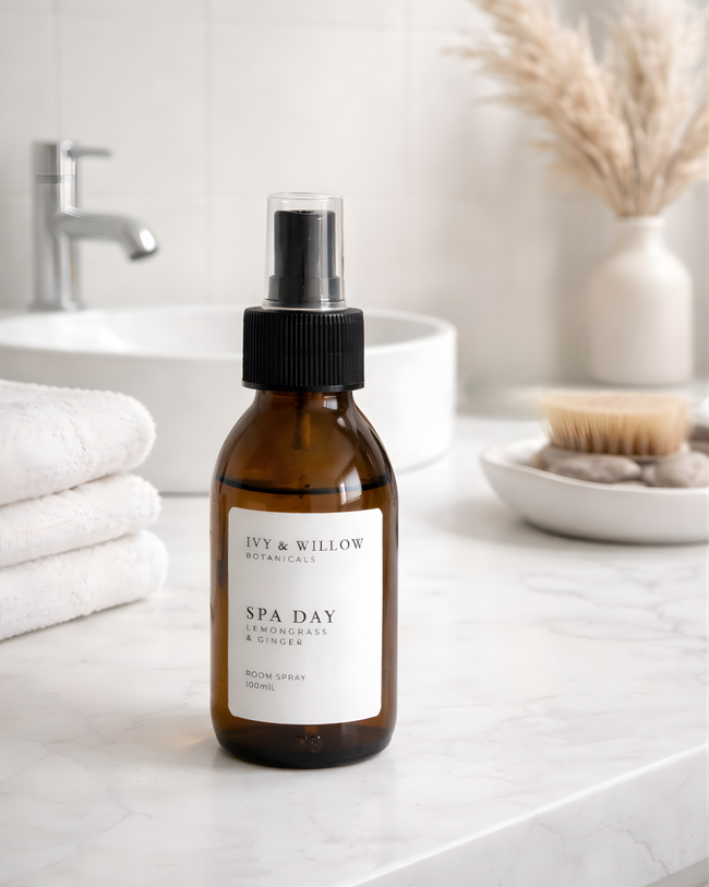 Bottle of Ivy & Willow product on a bathroom counter with towels and a sink in the background.