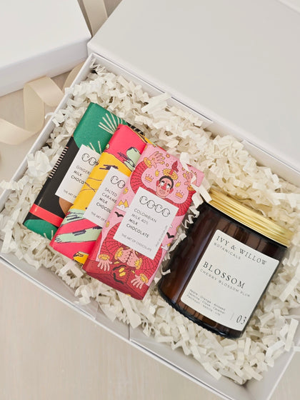 Box of chocolate bars and a candle with decorative packaging.