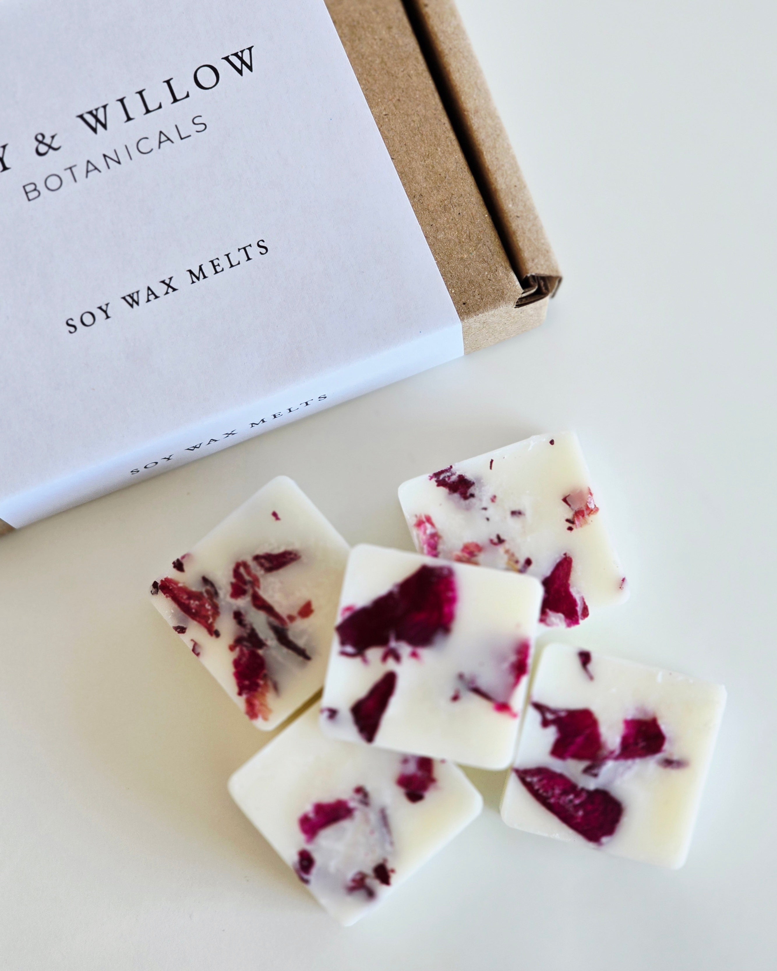 Soy wax melts with red flower petals next to a box labeled 'Lily & Willow Botanicals' on a light background.