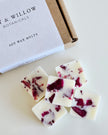 Soy wax melts with red flower petals next to a box labeled 'Lily & Willow Botanicals' on a light background.