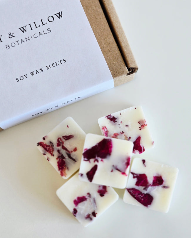 Soy wax melts with red flower petals next to a box labeled 'Lily & Willow Botanicals' on a light background.