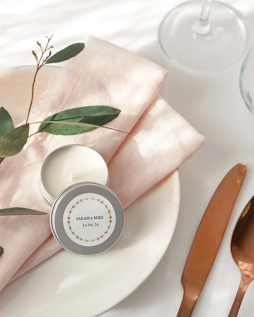 Small tin with a personalized label on a pink cloth with green leaves and a knife.