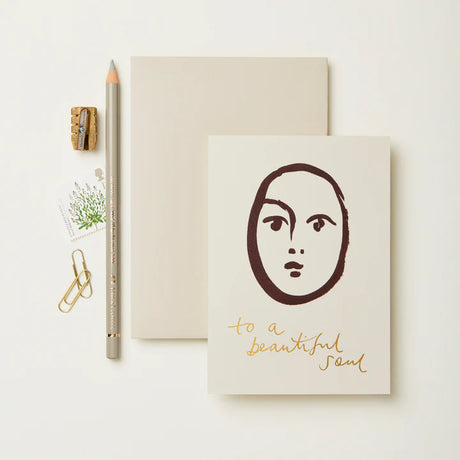 Notebook with face illustration and 'to a beautiful soul' text on a white background