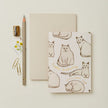 Notebook with cat illustrations, pencil, sharpener, and paper clips on a light background