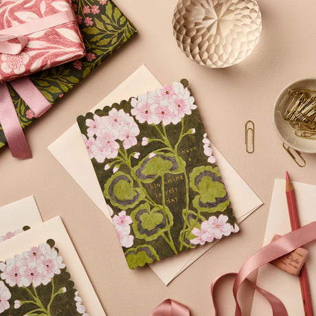 Floral notebook with stationery items on a beige surface