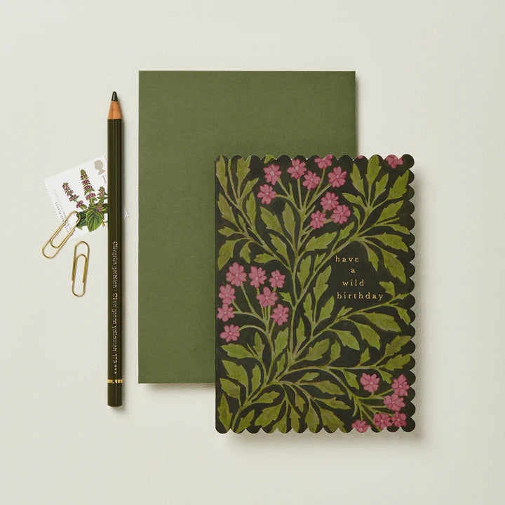 Green notebook with floral design and pencil on a light gray background
