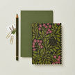 Green notebook with floral design and pencil on a light gray background