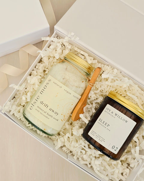 Two bath products in a gift box with white crinkle paper