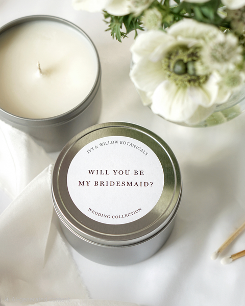 Candle in a tin with 'Will You Be My Bridesmaid?' question on a white background