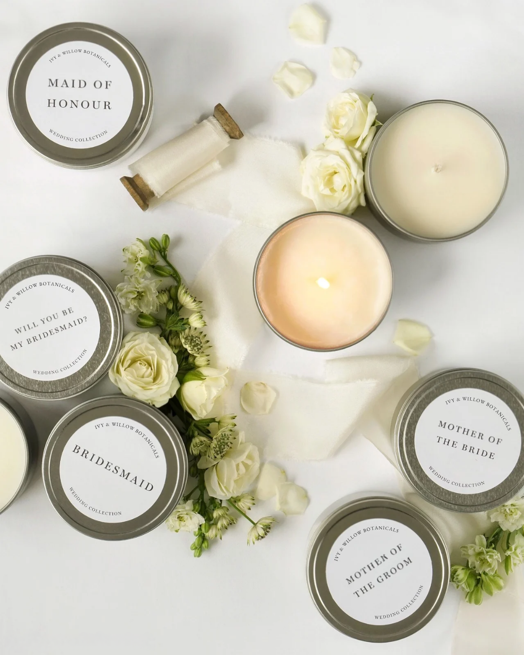 Candle set with personalized labels on a white surface with flowers.