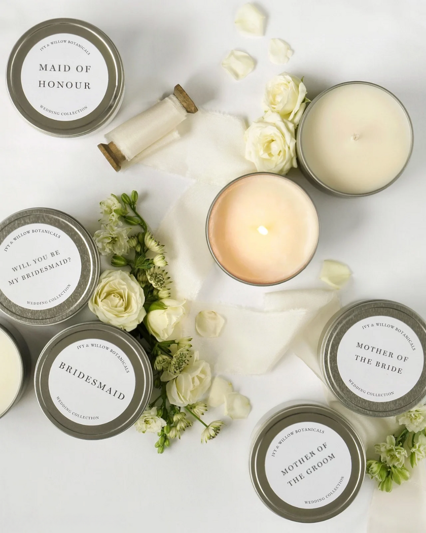 Candle set with personalized labels on a white surface with flowers.